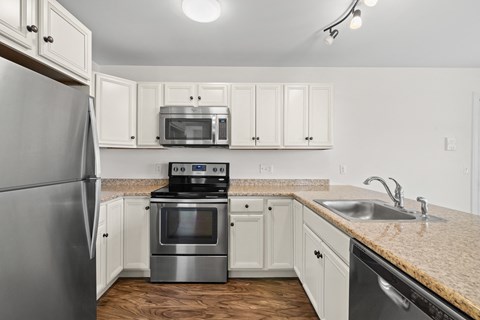 A kitchen with a stainless steel refrigerator and a microwave above the stove.