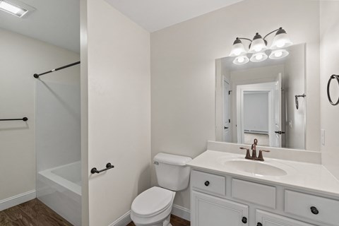 A white bathroom with a toilet, sink, and mirror.