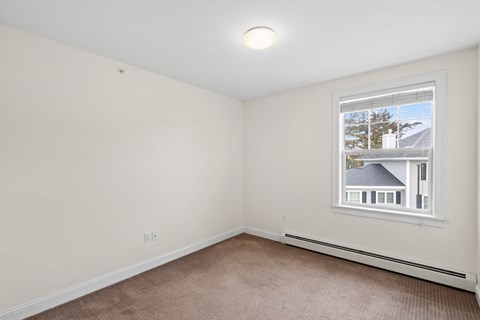 A room with a window showing a house outside.