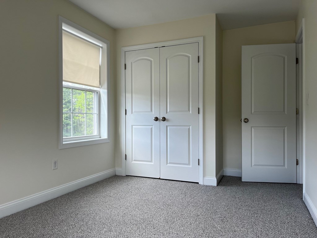 A room with two white doors and a window with blinds.