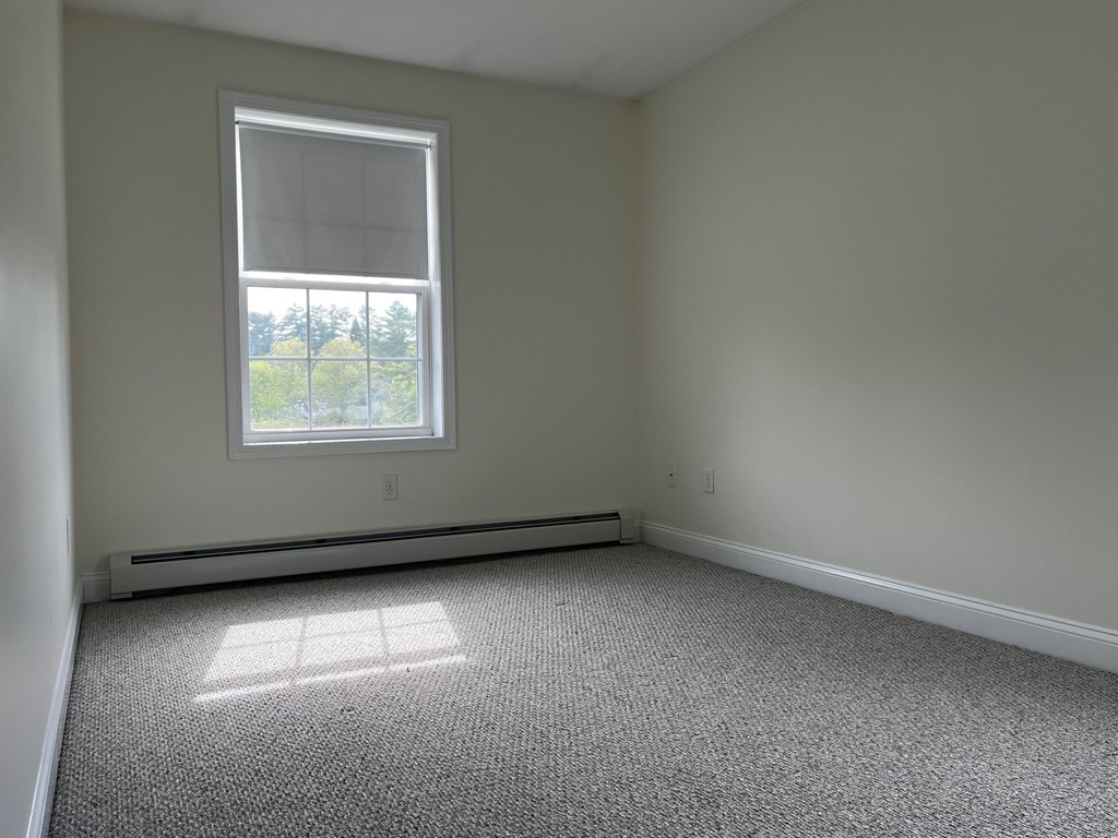 A room with a window and a carpeted floor.