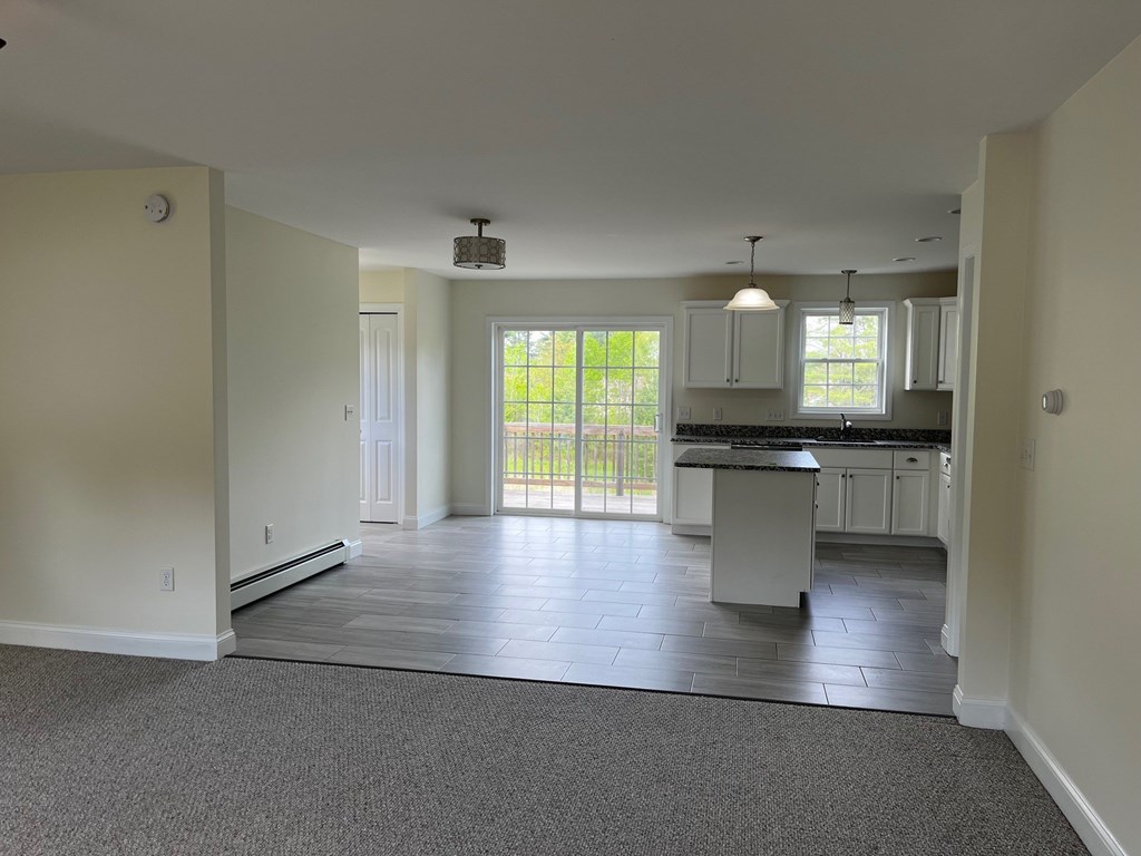 A spacious kitchen and living room with a sliding glass door leading to a backyard.