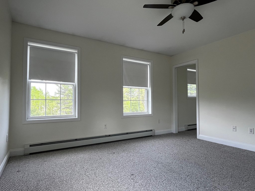 A room with a ceiling fan and two windows.