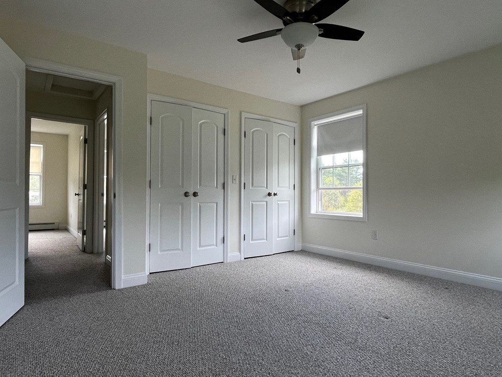 A room with a ceiling fan and carpeted floor.