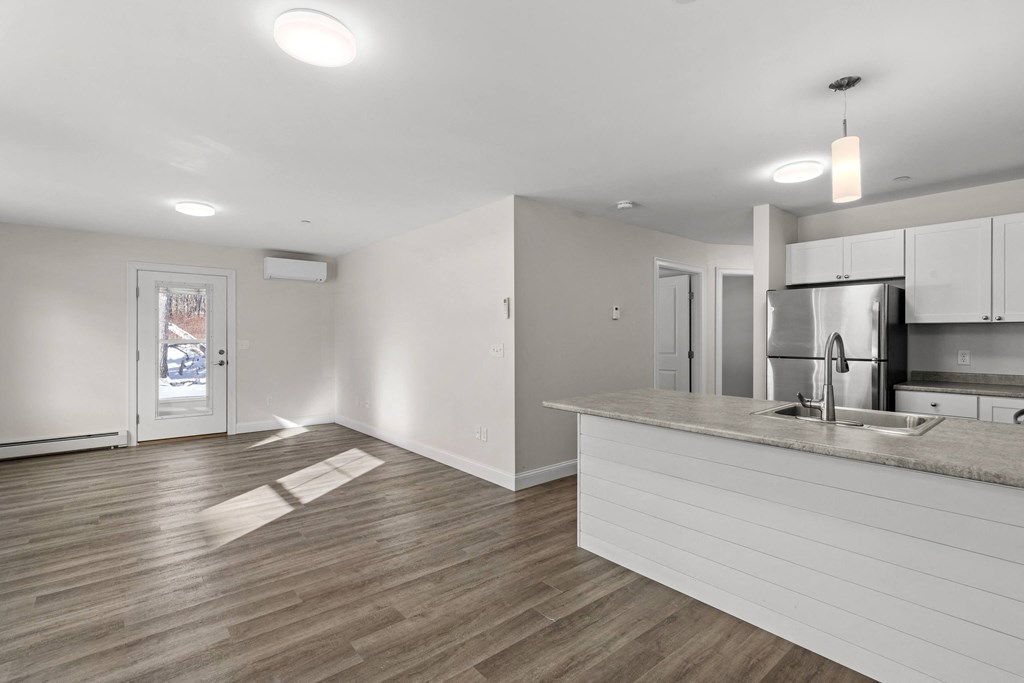 an empty kitchen and living room with a sink and a refrigerator
