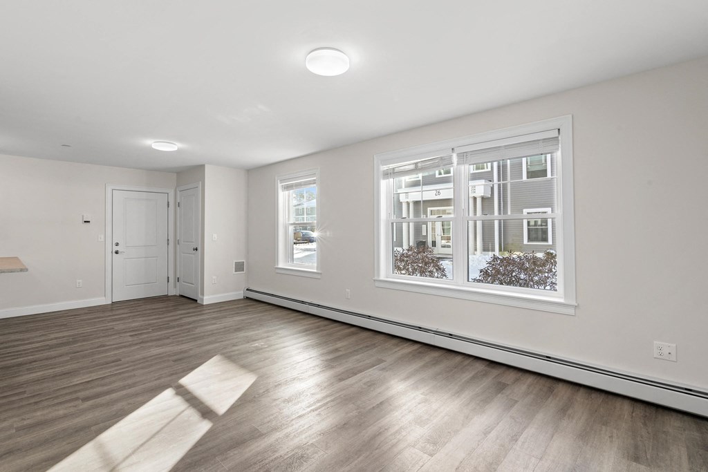 an empty living room with a large window and wood flooring