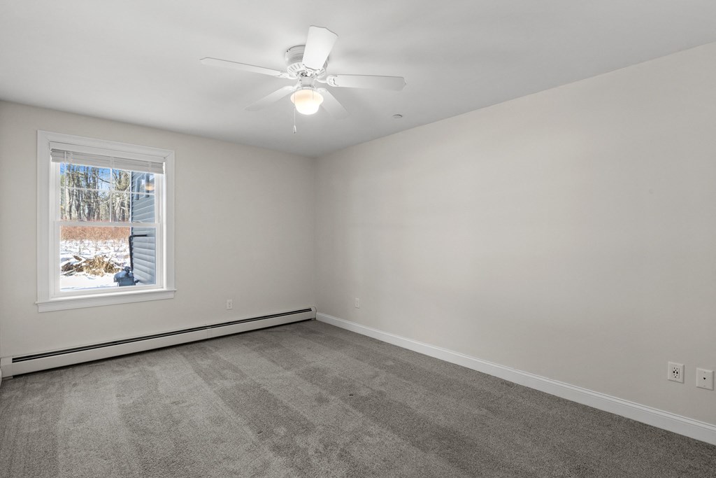 an empty living room with a ceiling fan and a window