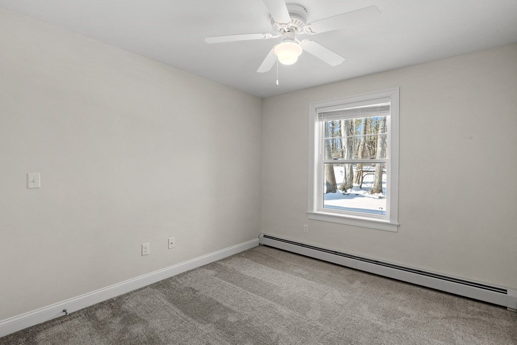 an empty living room with a ceiling fan and a window