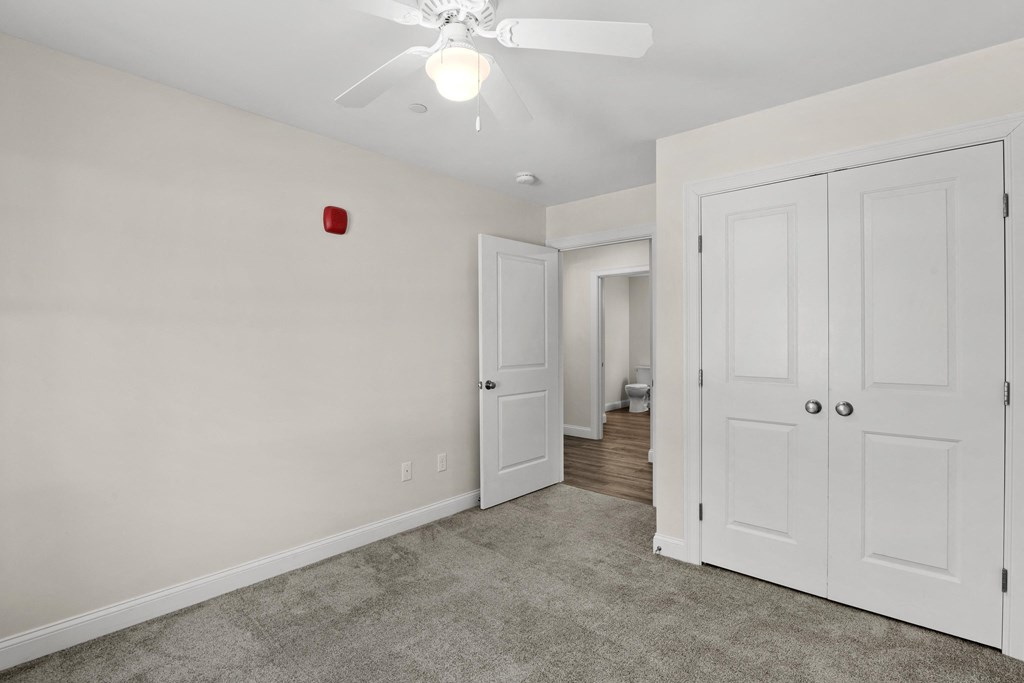 a renovated living room with white doors and a ceiling fan
