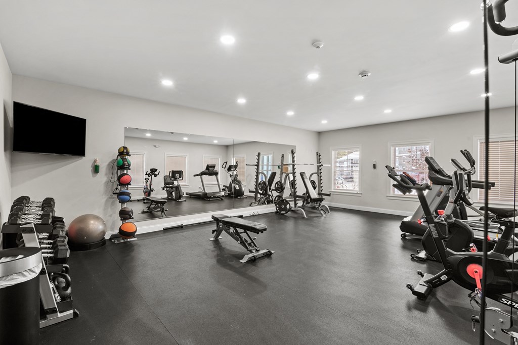 the gym has plenty of exercise equipment and a tv