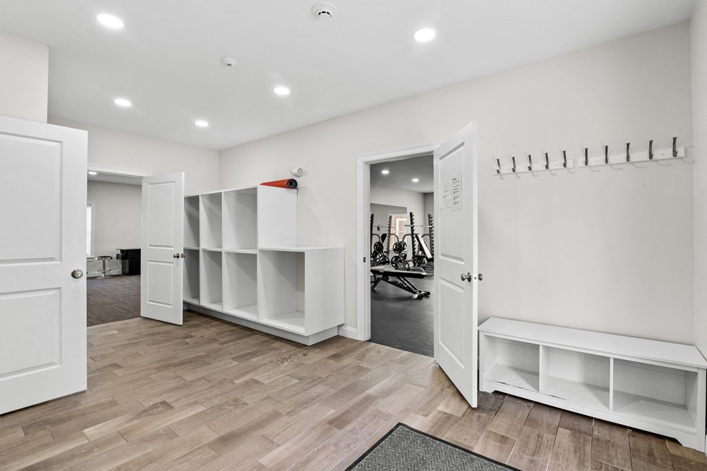 a room with white walls and shelves and a door to a workout room