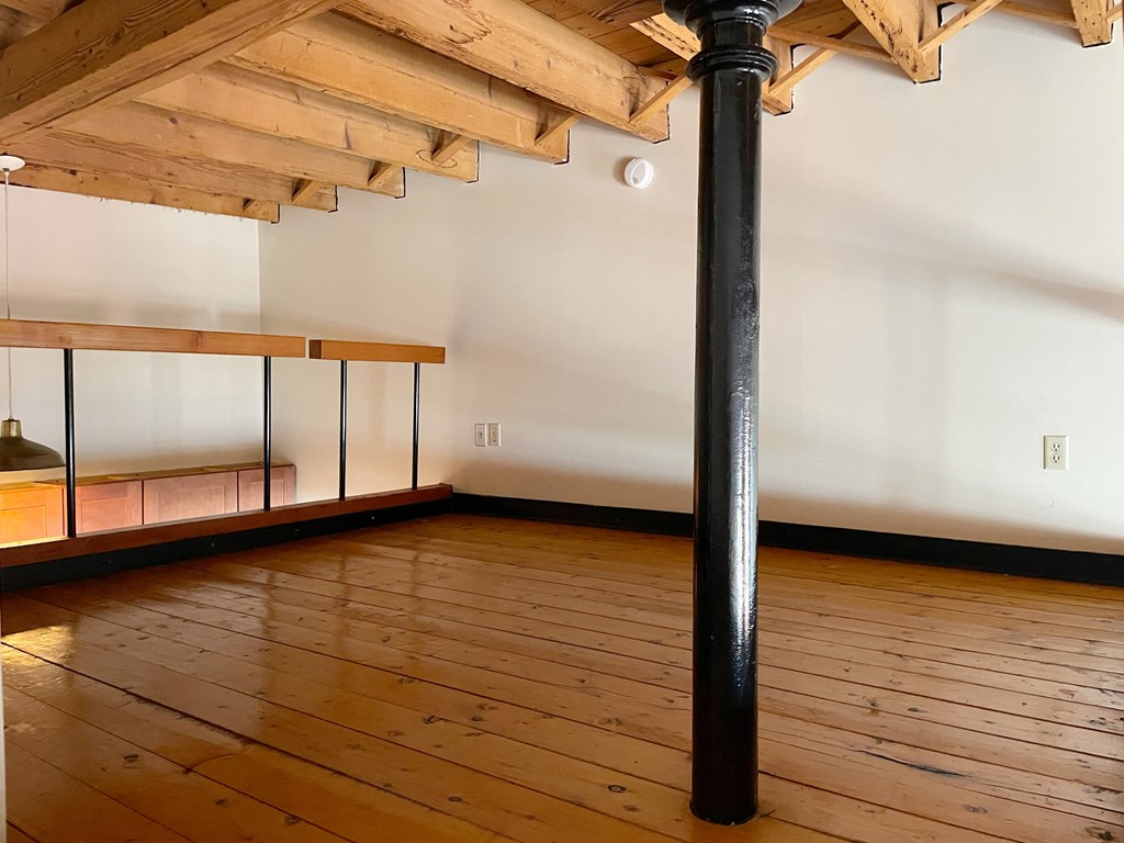 a loft with a black pole in the middle of a wooden floor