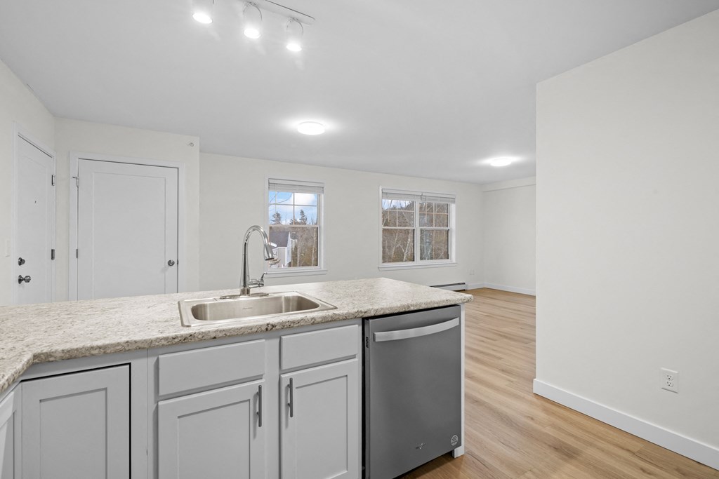 a renovated kitchen with white cabinets and granite counter tops and a sink