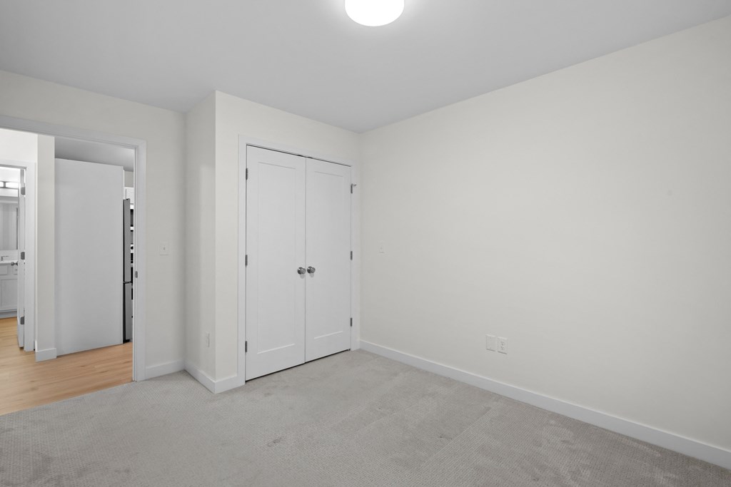 a bedroom with white walls and white doors and a carpeted floor