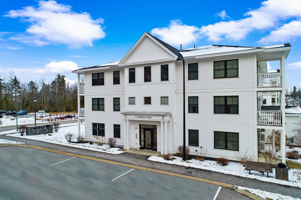 a large white apartment building with snow on the ground