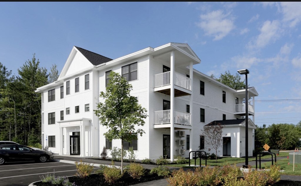a white apartment building with balconies and a parking lot