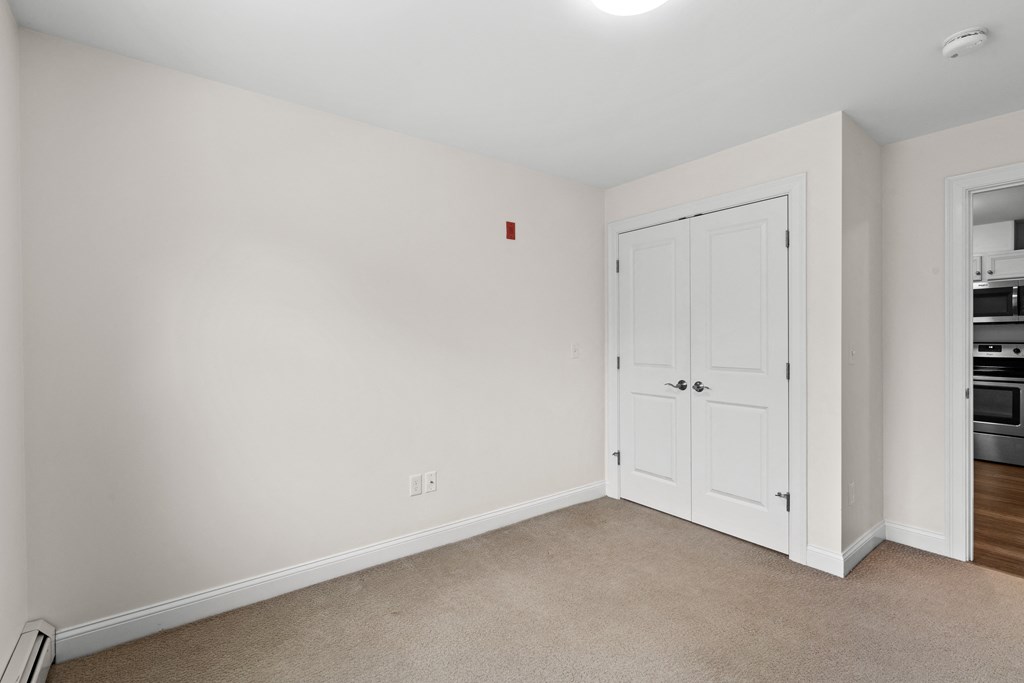 a bedroom with white walls and a door to a closet