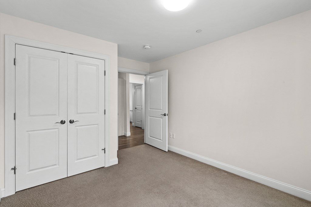 a bedroom with white closets and doors and a carpeted floor