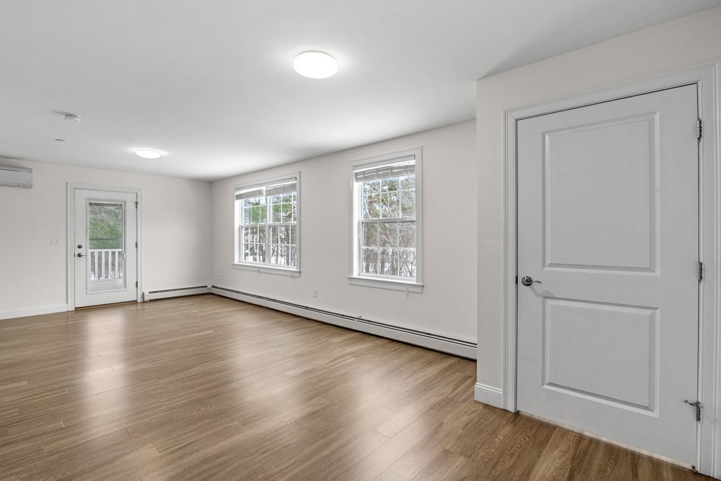 an empty living room with white walls and wood floors and a white door