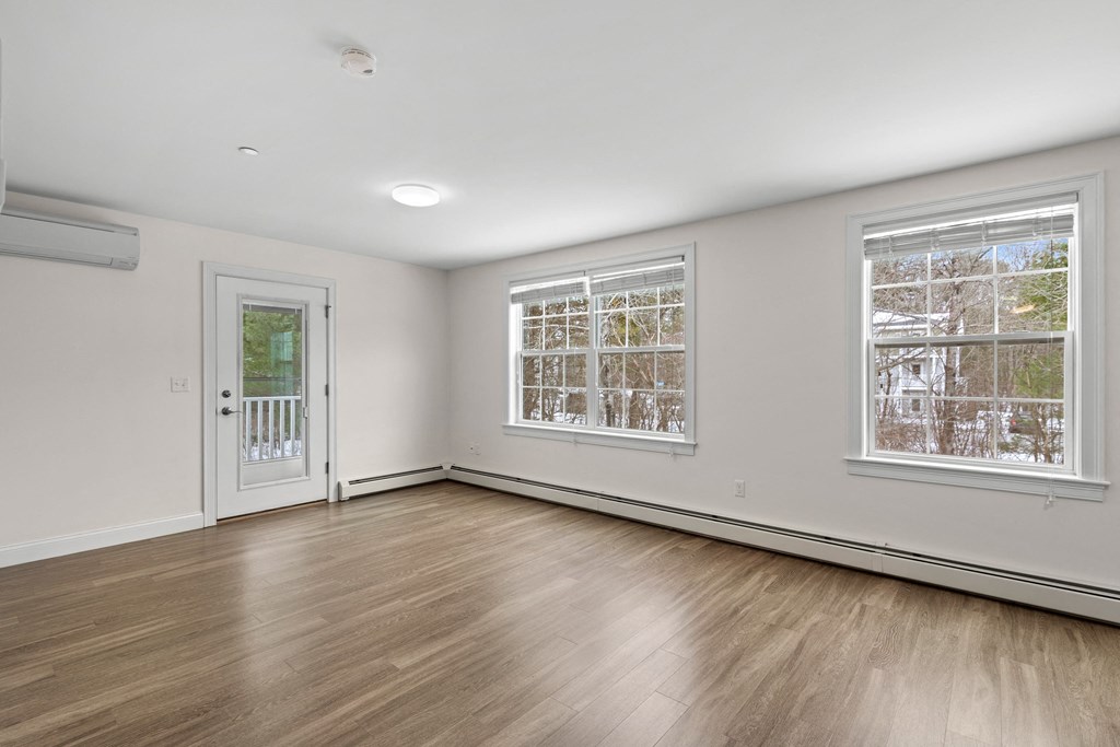 an empty living room with wood floors and white walls