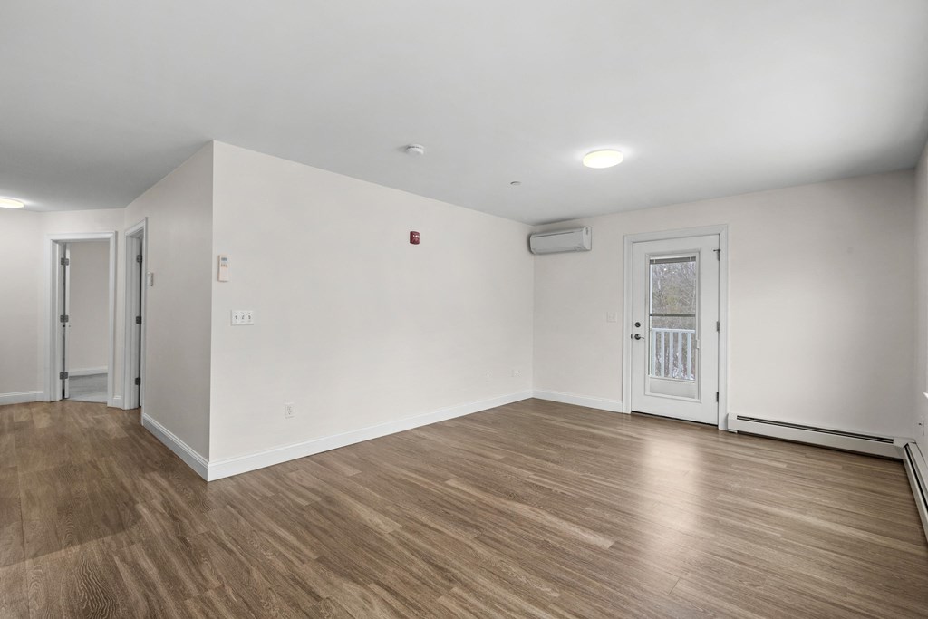 the living room of an empty apartment with white walls and wood floors