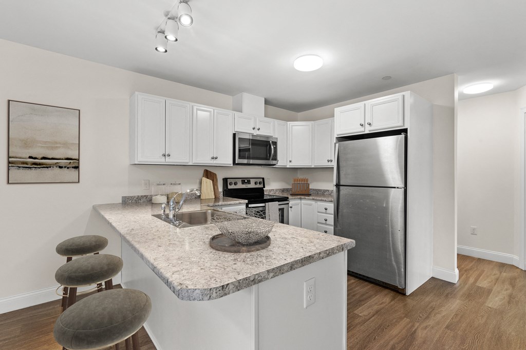 a kitchen with a granite counter top and a stainless steel refrigerator
