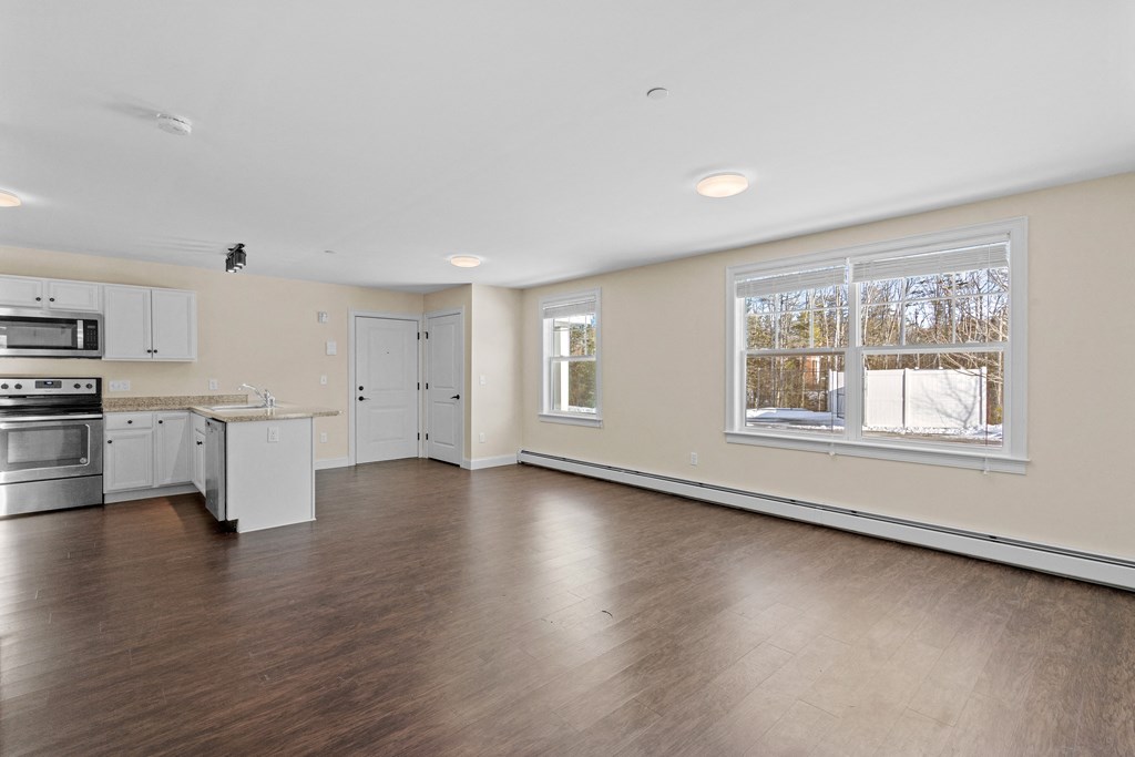 an empty kitchen and living room with wood floors and a large window