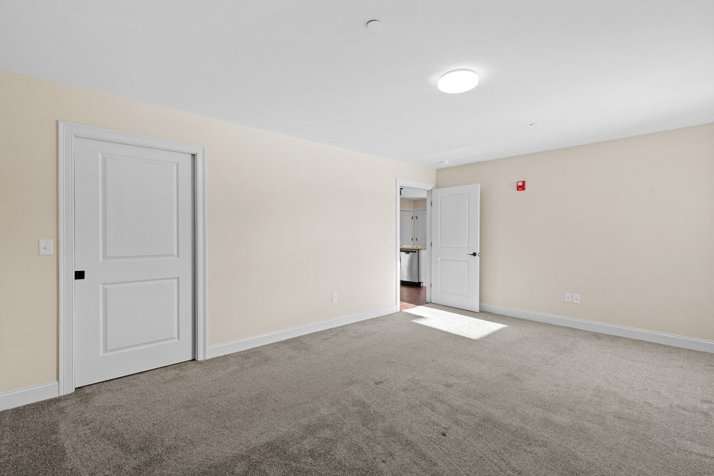an empty living room with white doors and a carpeted floor