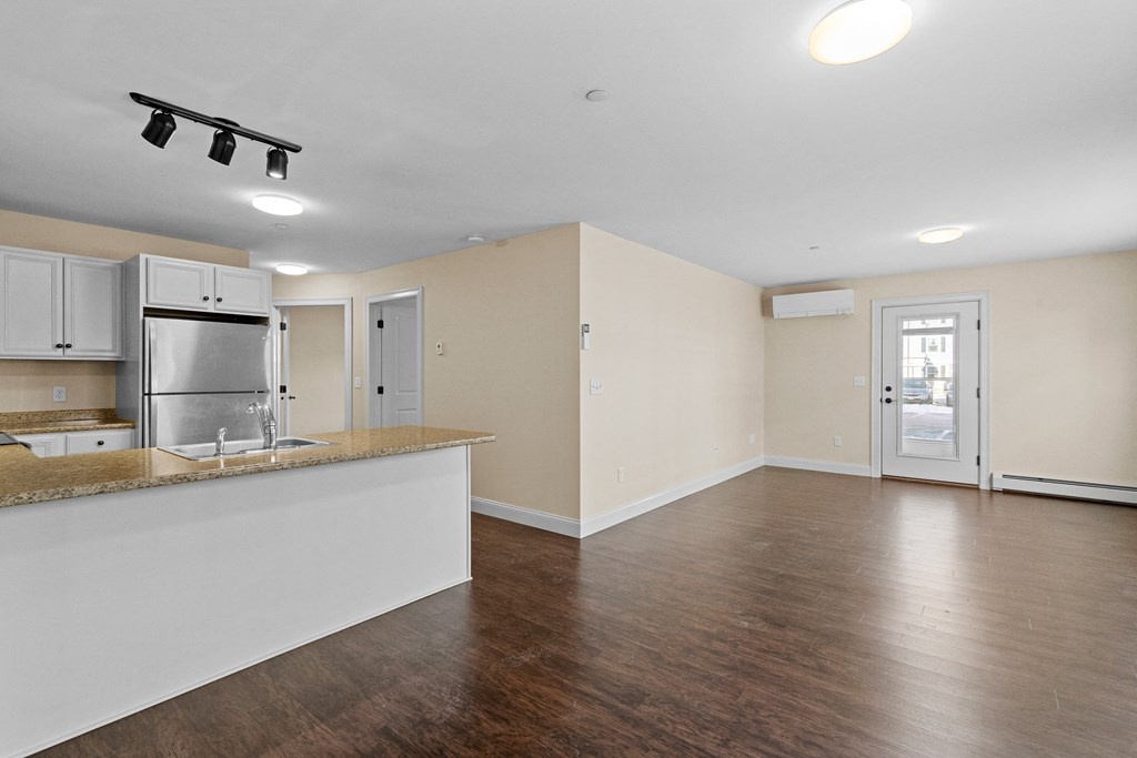 an empty kitchen and living room with hardwood flooring and an open floor plan