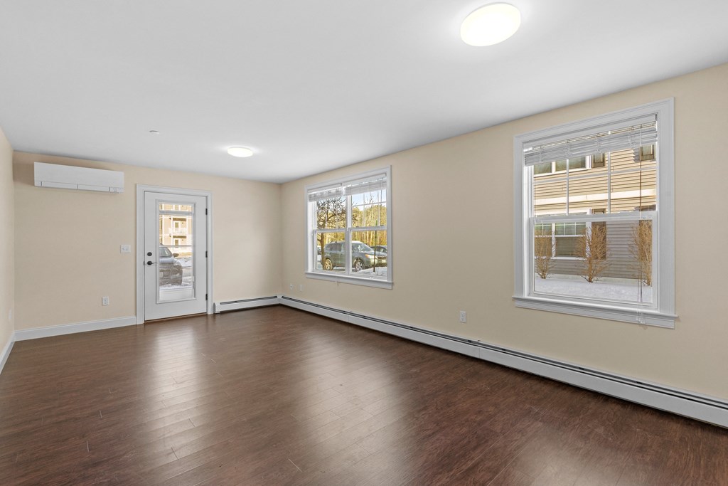an empty living room with wood flooring and a door to a hallway