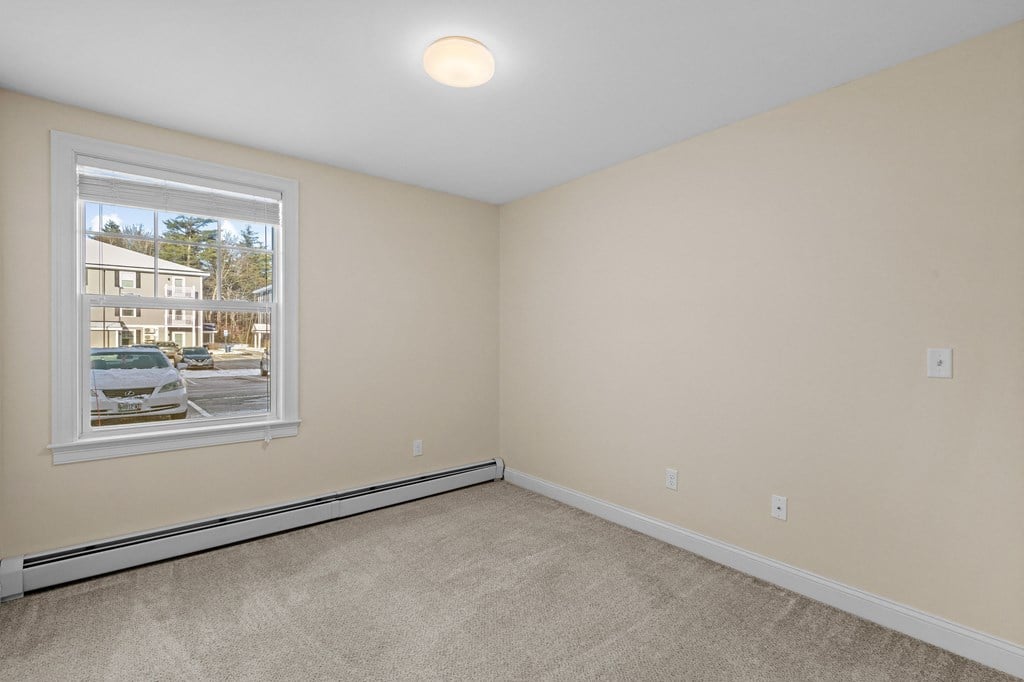 an empty bedroom with a large window and carpeting