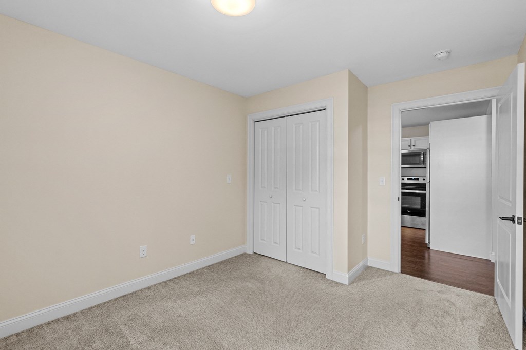 a bedroom with a closet and a door to a kitchen