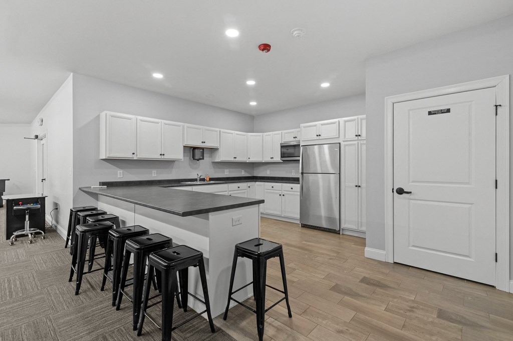 a kitchen with white cabinets and a large island with black counter tops