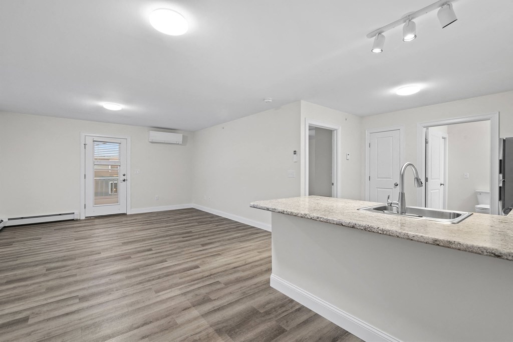 an empty living room and kitchen with a sink and a counter top
