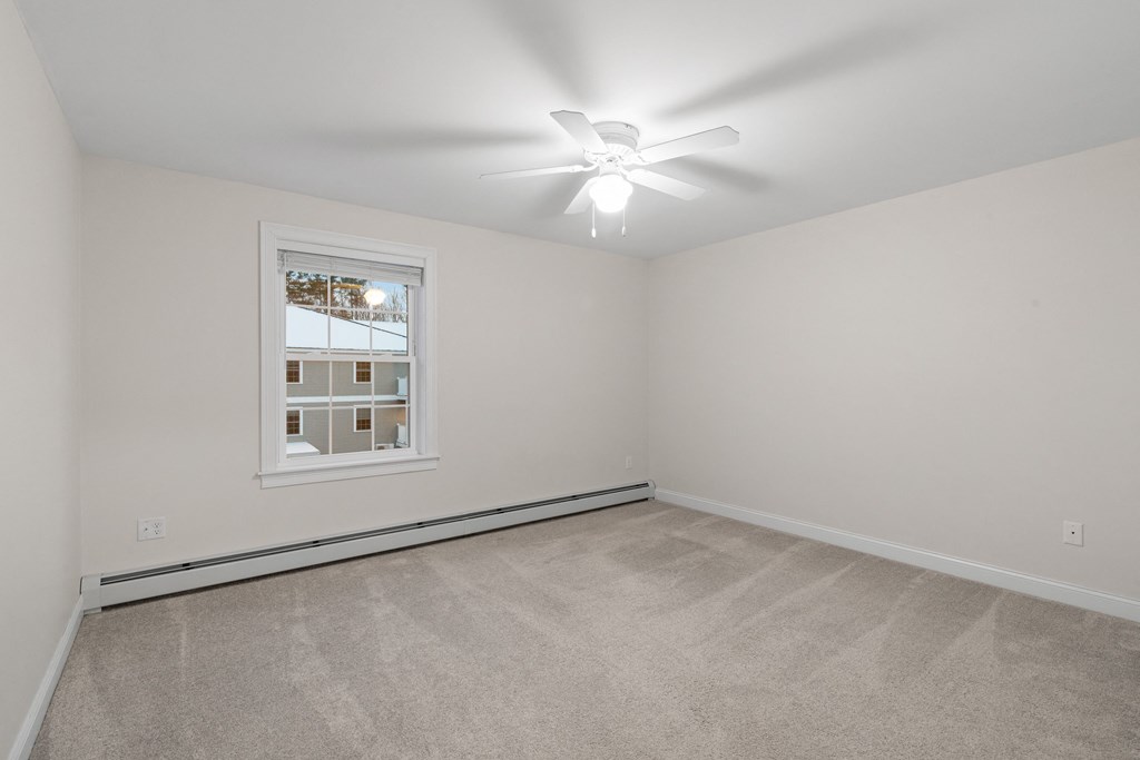 the living room of a home with carpet and a ceiling fan