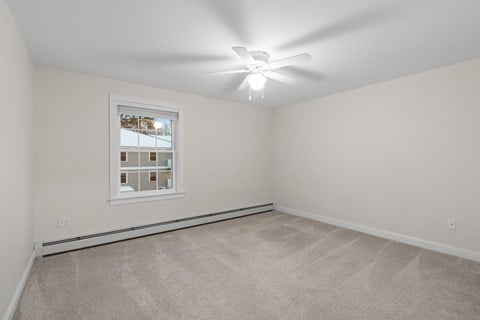 the living room of a home with carpet and a ceiling fan