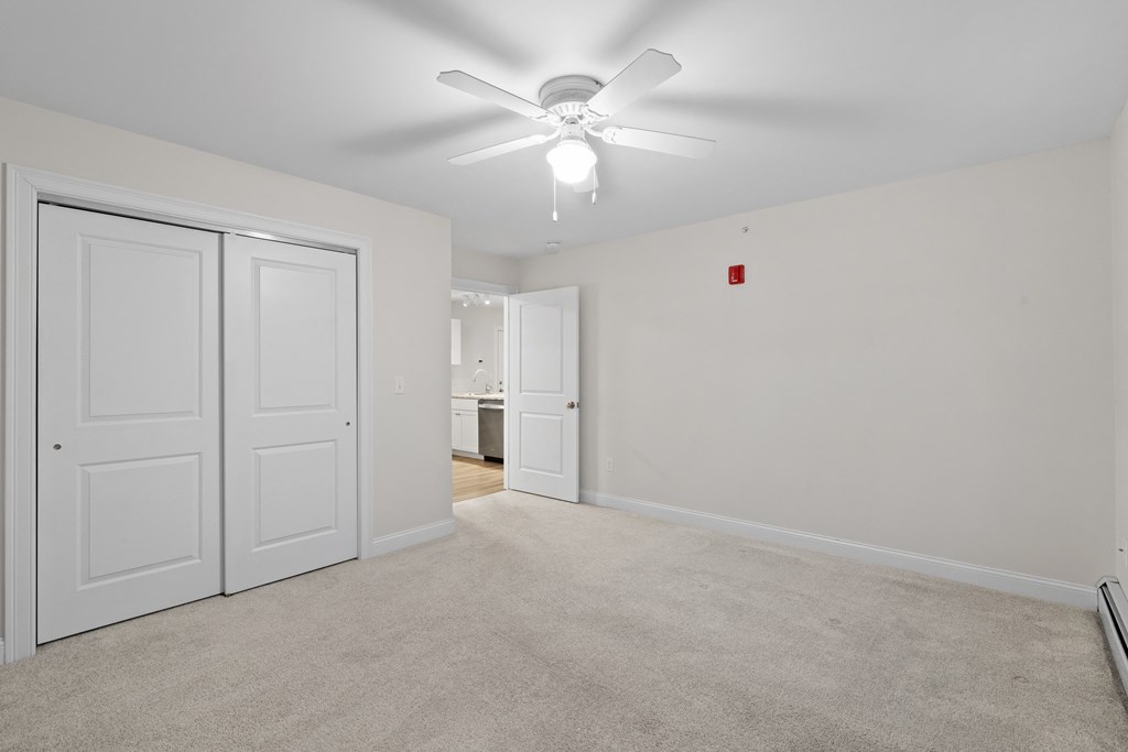 an empty living room with white walls and a ceiling fan