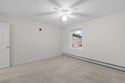 an empty room with a ceiling fan and a window