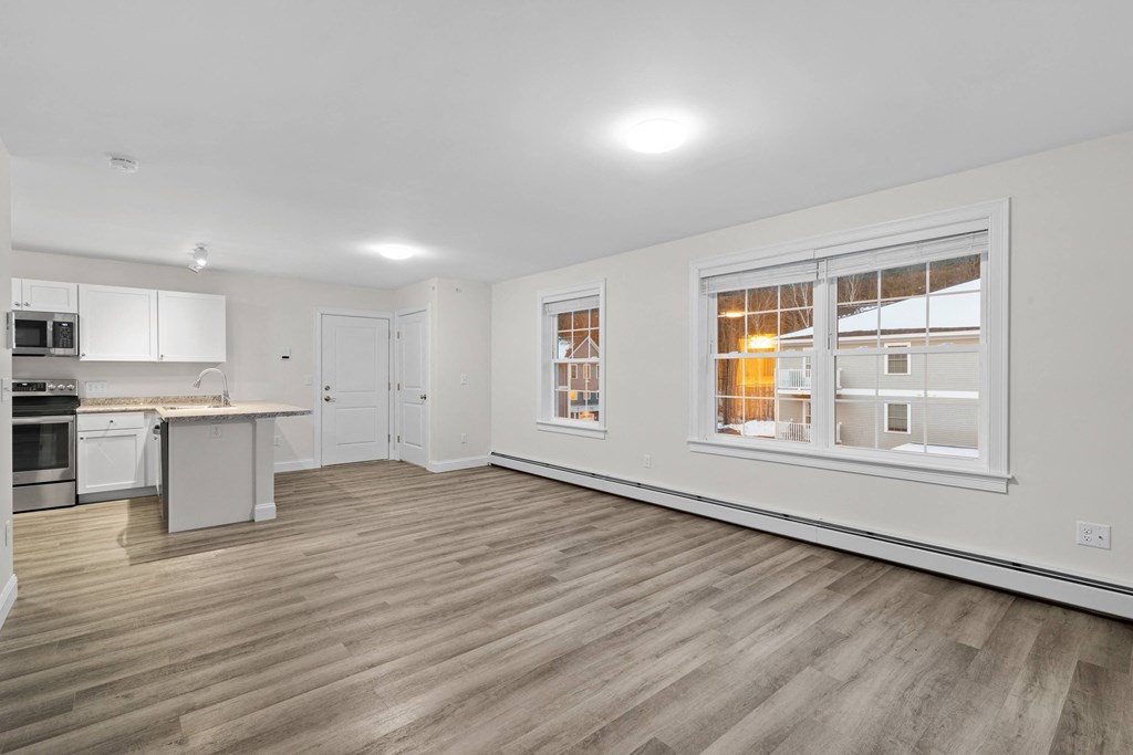 a living room with a large window and a kitchen