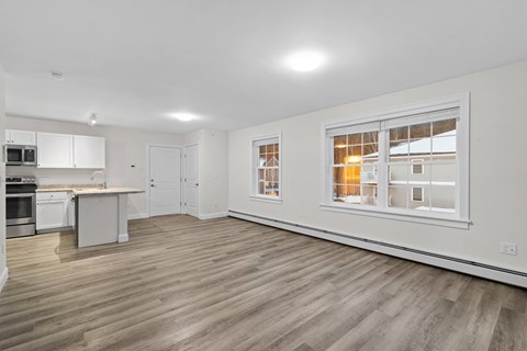 a living room with a large window and a kitchen