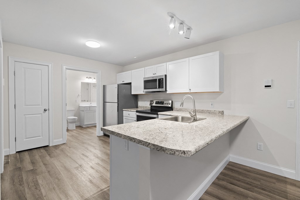 a kitchen with white cabinets and a marble counter top and a sink