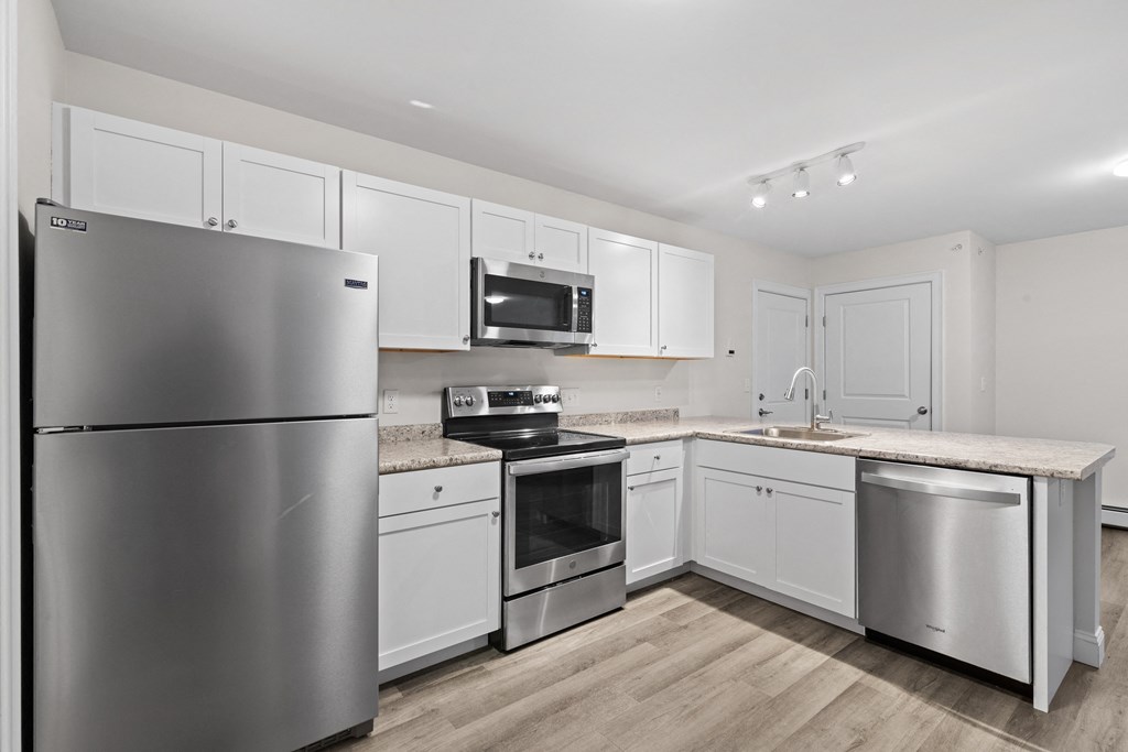 a white kitchen with stainless steel appliances and white cabinets