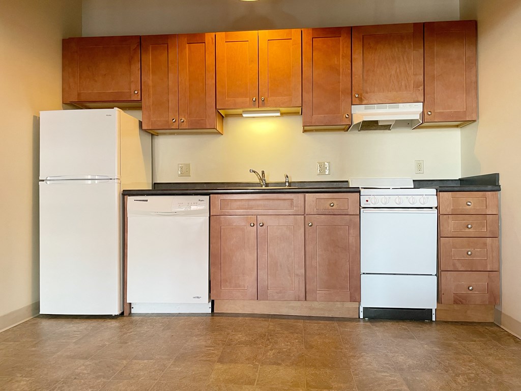 an empty kitchen with white appliances and wooden cabinets