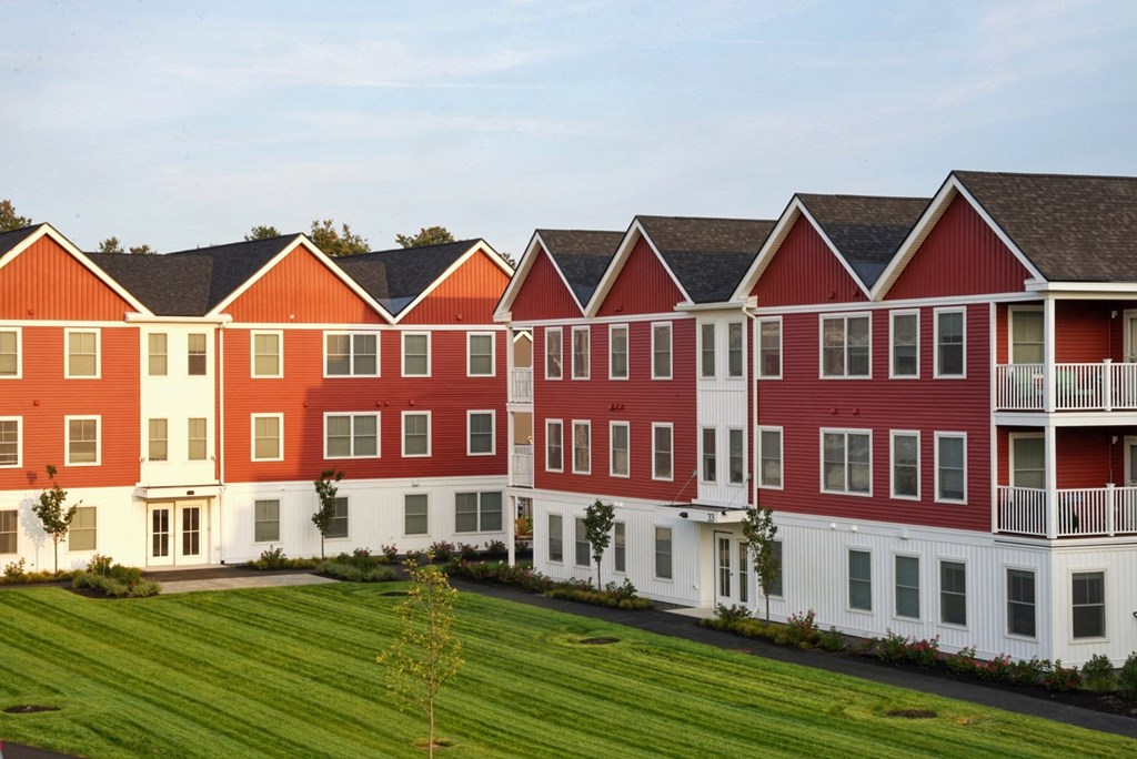 a row of red houses in front of a green field