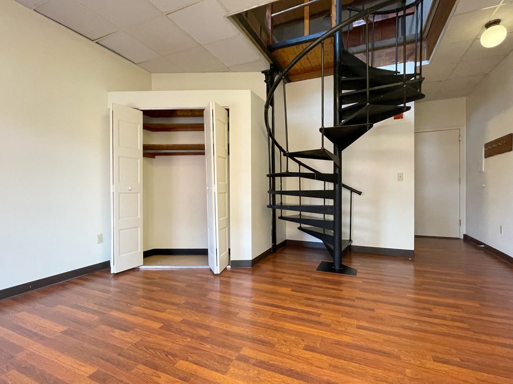an empty living room with a spiral staircase and a door to a closet