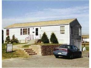 A white building with a car parked in front.