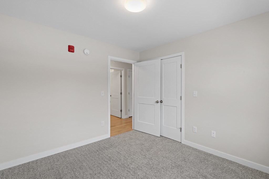a bedroom with white walls and white doors and a carpeted floor