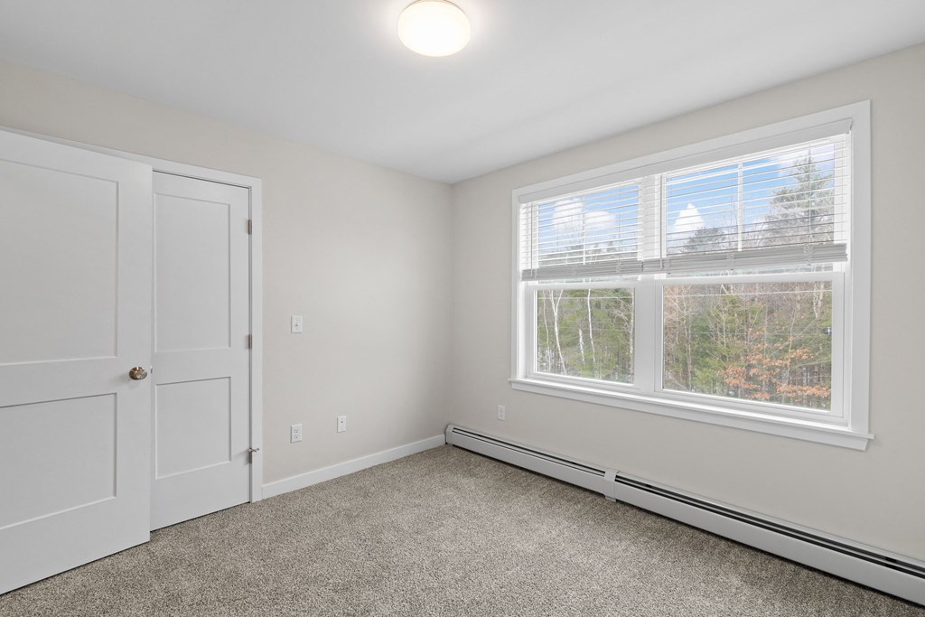 an empty bedroom with a window and a door