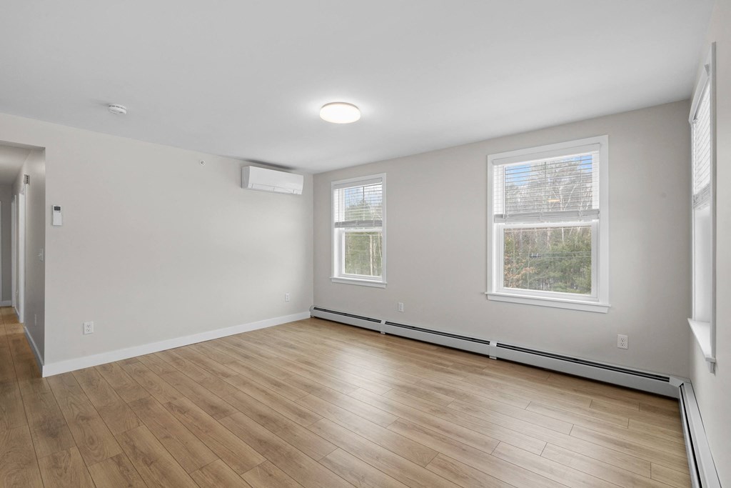an empty living room with wood flooring and two windows