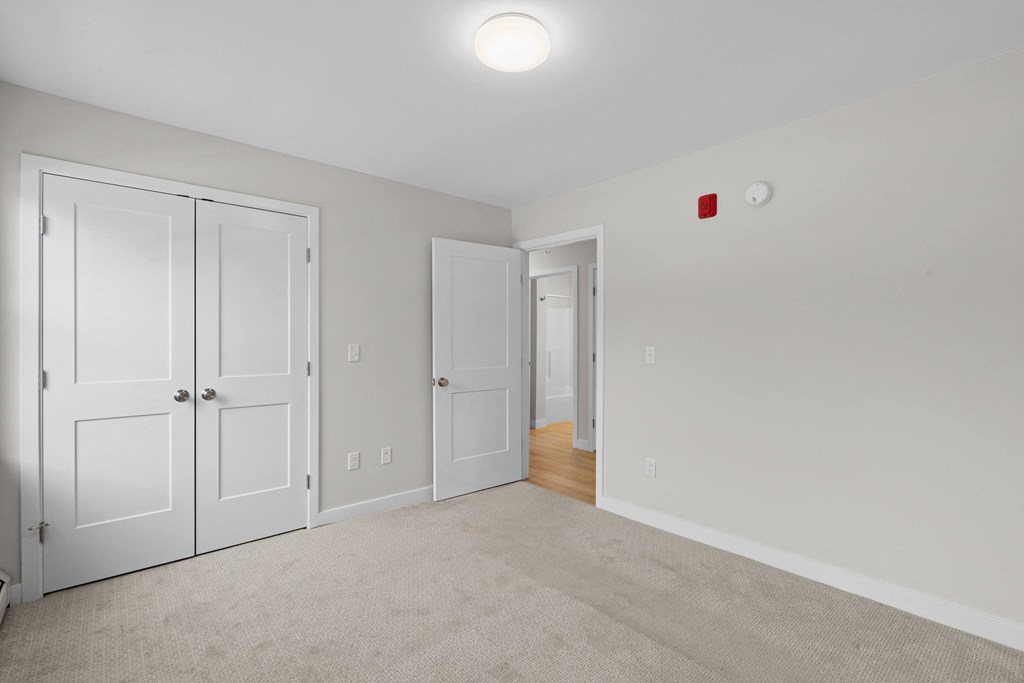 a bedroom with white doors and carpeting and a door to a hallway